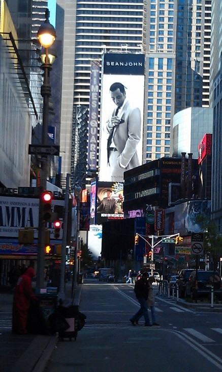 A photo of Times Square, with a giant billboard featuring Sean Combs in a suit looming over all.