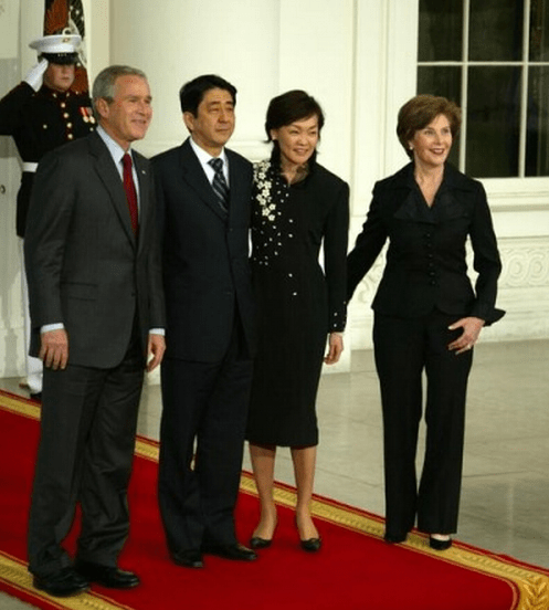 A photo of Shinzo Abe and President Bush, posing with their wives on a White House red carpet