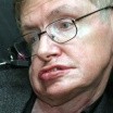 Photo of Stephen Hawking, in wire-frame glasses, his eyes bright but face twisted and distorted by ALS