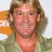A sunburned man with chest hair smiles broadly