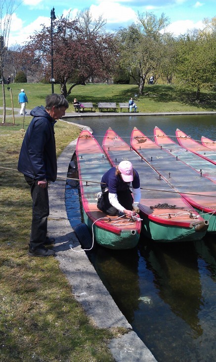 A worker kneels on the pontoon of a swan boat