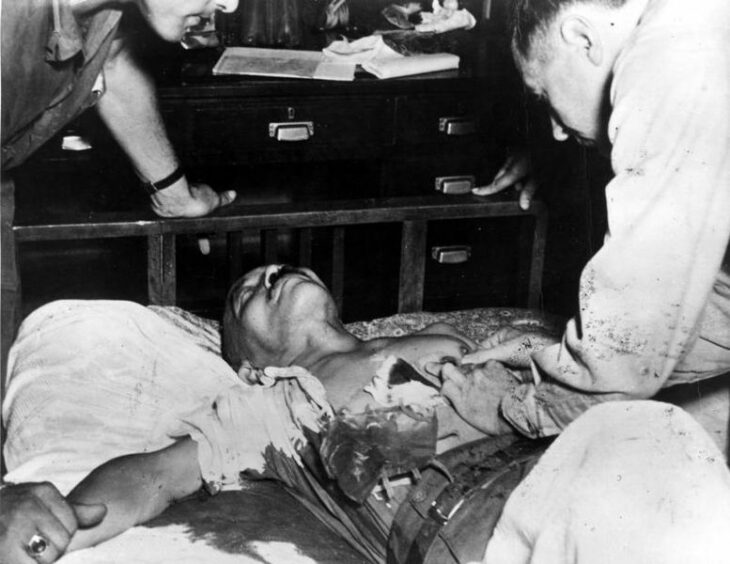 Hideki Tojo photo, with Tojo lying on his back in a bloody shirt and a doctor examining him