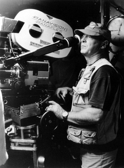 Photo of Tony Scott looking into a Panavision camera, wearing a fishing vest