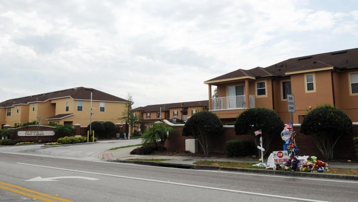 Photo of a suburban gated village, with stucco-type apartments on a busy street