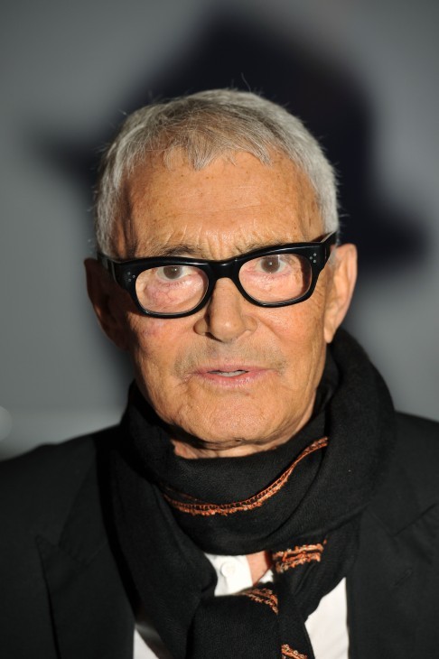 A photo of Vidal Sassoon, much older, but in a stylish black jacket and groovy muffler
