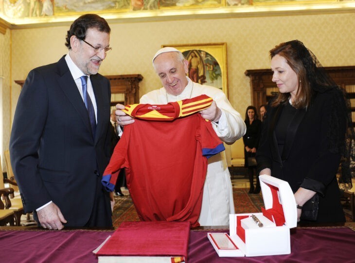 Pope Francis photo, with the pope holding up a red soccer jersey and smiling