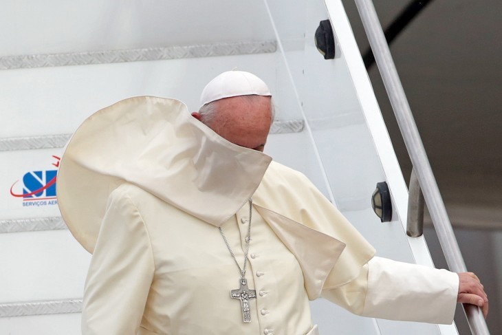 Photo of Pope Francis with his robe whipped over his face by the wind