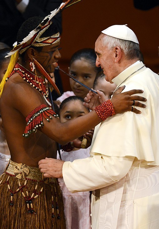 Pope Francis hugs a man in elaborate tribal garb and ribbons