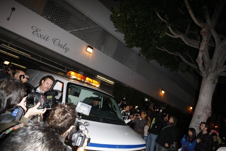 An ambulance with Whitney Houston's body leaves a hotel garage under the words 