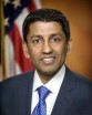 Sri Srinivasan in a blue suit with blue tie and white shirt, in front of a U.S. Flag