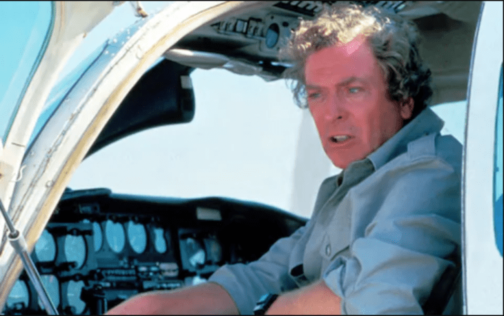 Michael Caine looks frantic as he sits in the open cockpit door of a small plane