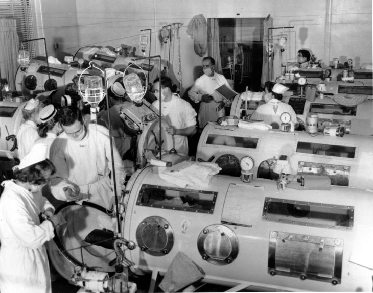 This is a scene in the emergency polio ward at Haynes Memorial Hospital in Boston, Ma., on Aug. 16, 1955. The city's polio epidemic hit a high of 480 cases. The critical patients are lined up close together in iron lung respirators so that a team of doctors and nurses can give fast emergency treatment as needed. (AP Photo)