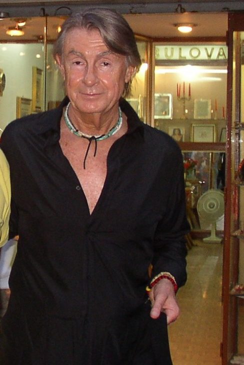 Joel Schumacher looks disheveled and sweaty, as if caught by surprise on a day off, as a fan snaps a photo