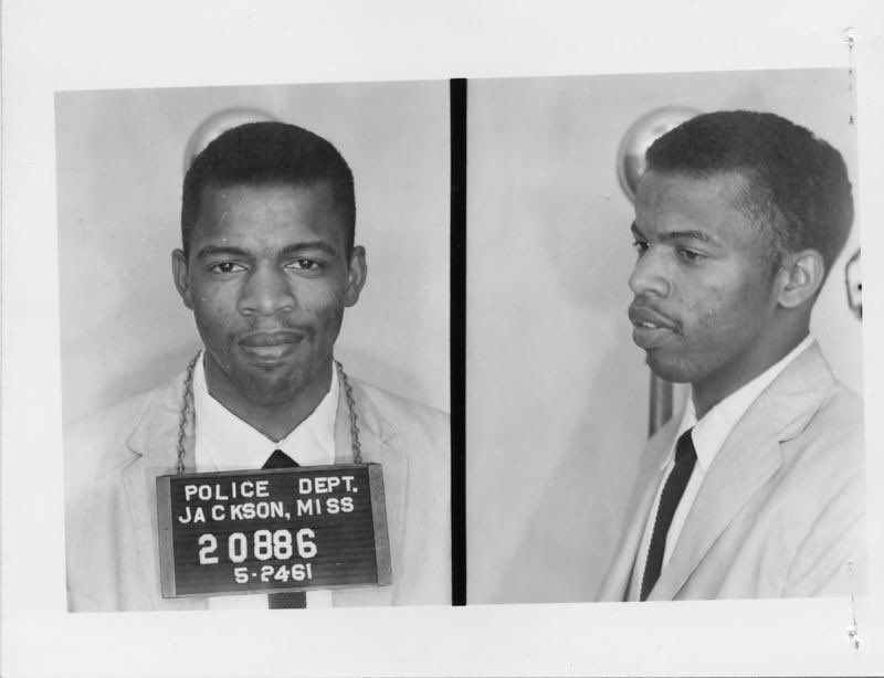 John Lewis is seen in front and side views, smiling slightly. He wears a mug shot board around his neck in the first photo, reading "Police Dept. Jackson Miss. 20886 / 5.24.61"