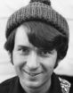 Michael Nesmith is a smiling young man with a shock of dark hair sticking out from under his knitted wool cap