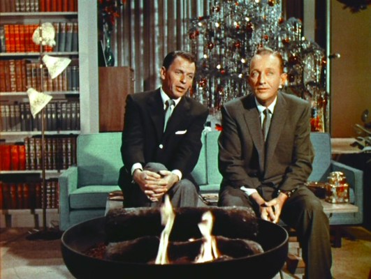 Frank Sinatra and Bing Crosby sit in a mod living room with a tree behind them, singing. (They're singing, not the tree.)