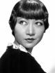 Anna May Wong is a handsome young woman with short, close-cropped hair. She looks back over her shoulder and off-camera in this staged glamour shot.
