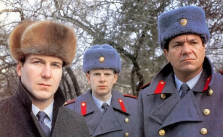 Three policeman in fur hats look puzzled while standing in a park